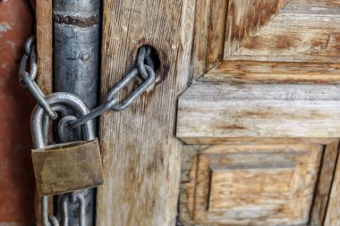 Ahşap bir kapı tutmak için bir zinciri tutarak asma kilit kapalı