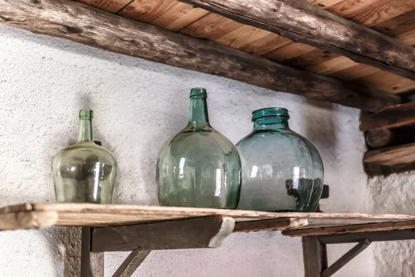 Three wide bottles of green glass, on an old shelf in a very old house, Spain