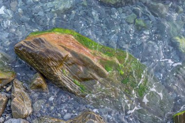 Farklı renkteki kristal berraklığında suları ile çevrili büyük kaya