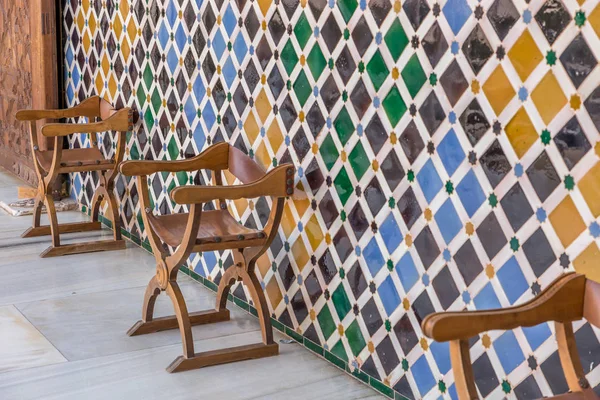 Chairs and the wall of mosaic in The Alhambra, Granada, Spain
