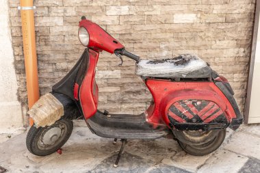 Eski bir sokakta park edilmiş birçok yamalar ile çok eski kırmızı İtalyan tarzı motosiklet