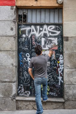 A man observes graffiti painted on a metal door