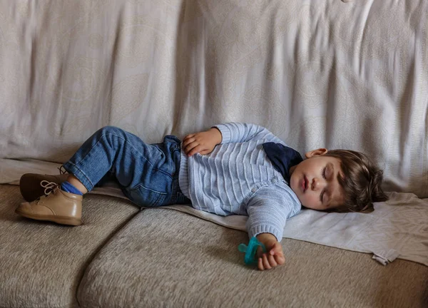Симпатичный и маленький мальчик, одетый в синие и коричневые туфли, спит — стоковое фото