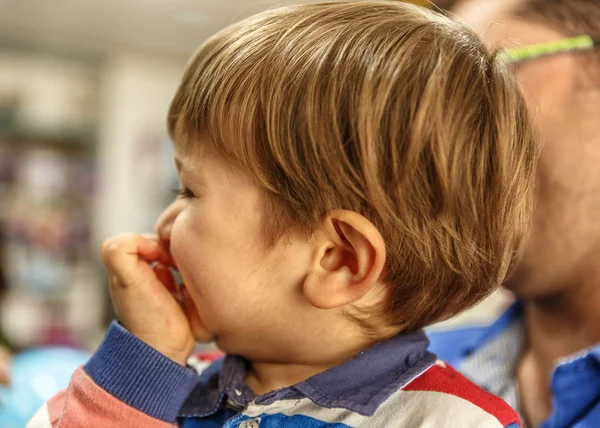 Un niño lindo sonríe en los brazos de su padre — Foto de Stock