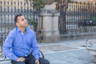 Mavi gömlek şık bir adam ortasında bir bankta oturan bekler