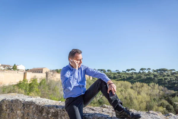 Zarif bir iş adamı eteklerinde cep telefonu tarafından konuşuyor 