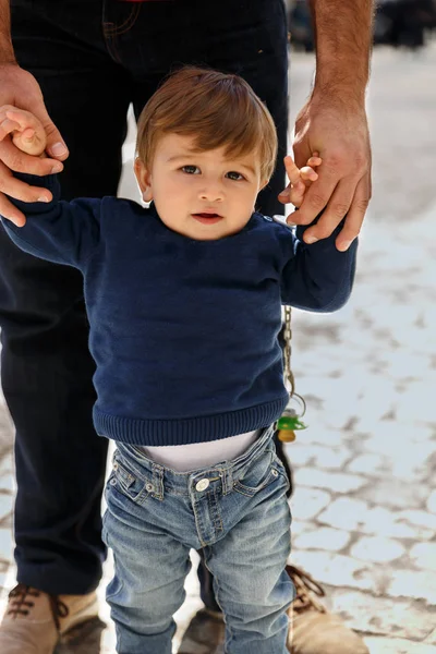 Um menino aprendendo a andar da mão de um adulto — Fotografia de Stock