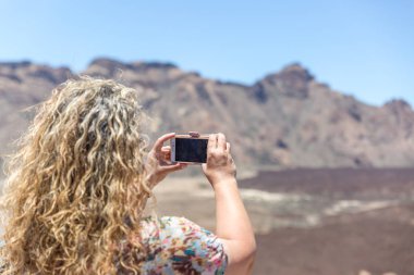Olgun bir sarışın turist bir çöl ve volca fotoğraf çekiyor