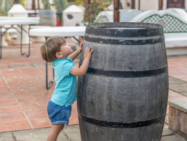 Mavi giyinmiş hoş bir çocuk bir varil ile oynar