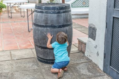 Mavi oyunlar giymiş hoş bir çocuk bir varil arkasında gizlemek