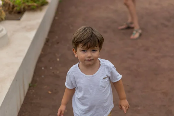 Retrato de un chico rubio lindo mientras camina por un sendero —  Fotos de Stock