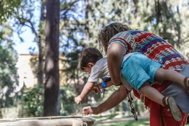 Bir anne küçük oğlunu kollarında taşır. 