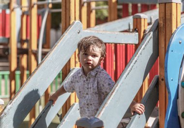 Sevimli bir sarışın bebek mutlu güzel bir parkın bir slayt aşağı süzülür