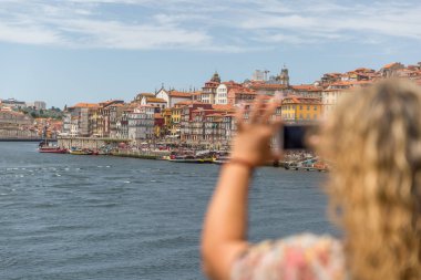 Sarışın bir turist kadın bir cep telefonu ile fotoğraf çeker 