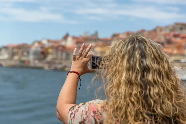 Sarışın bir turist kadın bir cep telefonu ile fotoğraf çeker 