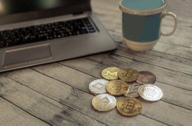 Kripto pazarının ana kripto para birimleri: bitcoin, ethereum, litecoin, dash, monero, ripple, iota, vintage bir masada, bir dizüstü bilgisayar ve mavi bir fincan yanında