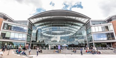 Girişte oturan birkaç kişi ve diğerleri yürüyüş ile kütüphanenin cephe görünümü