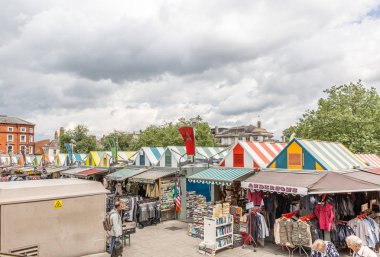 Typical English outdoor market with stands selling clothes and books clipart