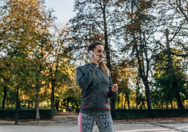 Mujer Rubia Joven Chándal Deportivo Sonríe Mientras Habla Teléfono Inteligente — Foto de Stock