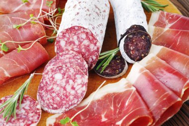 Yakın çekim et lezzetleri, İtalyan sosisi ahşap oyun tahtası ve jamon ince dilimler.