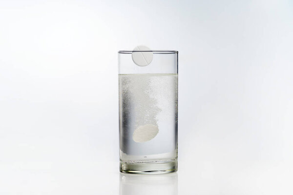A glass with effervescent tablets on a white background.