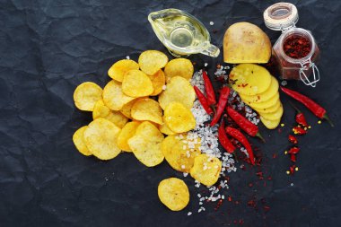 Üstten görünüm patates cipsi ve malzemelerin bir siyah Kağıt arka plan üzerine.