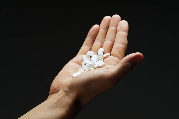 Un puñado de pastillas en la mano masculina sobre un fondo oscuro . —  Fotos de Stock