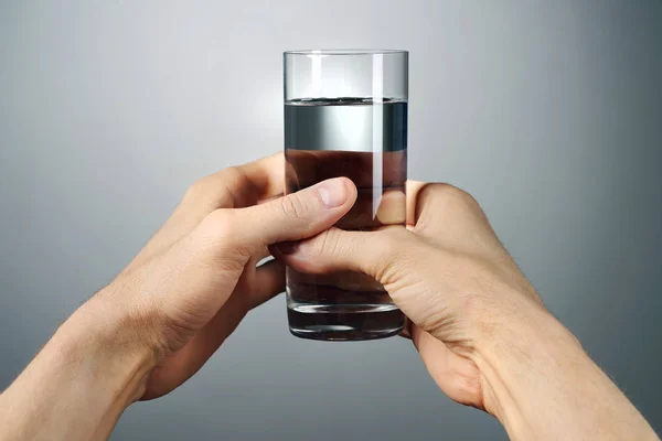 Glas Water Uitgerekt Door Mannelijke Handen Een Grijze Achtergrond Perspectief — Stockfoto
