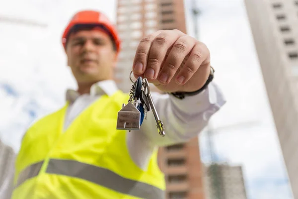 Imagen de primer plano del hombre de negocios de pie en el sitio de construcción y mostrando las llaves de la nueva casa —  Fotos de Stock