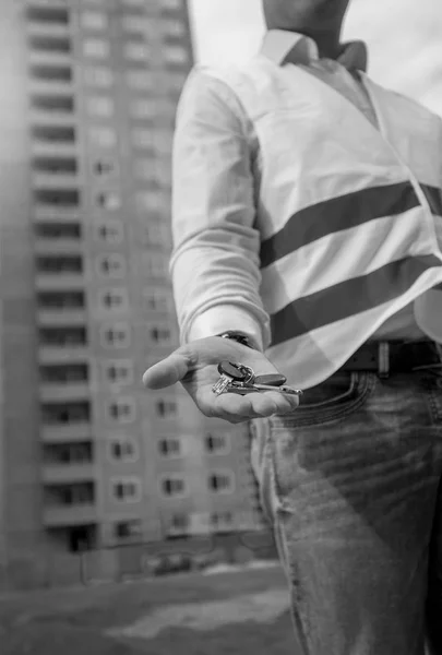 Imagen en blanco y negro de primer plano del arquitecto masculino sosteniendo las llaves de un nuevo apartamento a mano —  Fotos de Stock