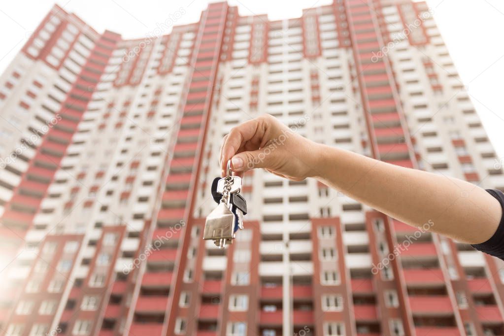 Closeup image of young woman showing keys from new apartment. Concept of real estate investment