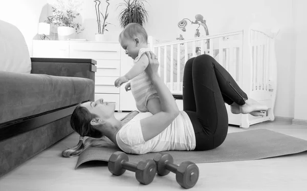 9 aylık bebek oğluyla evde egzersiz genç kadının siyah beyaz resim — Stok fotoğraf