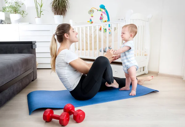 Χαριτωμένο 9 μηνών αγοράκι άσκηση με νεαρή μητέρα σε χαλί γυμναστικής στο σπίτι — Φωτογραφία Αρχείου
