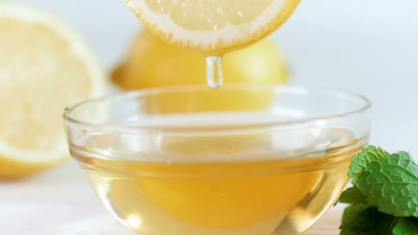 Крупный план замедленной съемки меда медленно капающего из ломтика лимона в стеклянную банку — стоковое видео