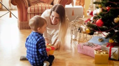 mutlu Genç Anne onun 3 yaşında yürümeye başlayan çocuk Noel hediye kutusunda sabah vermek 4 k görüntüleri