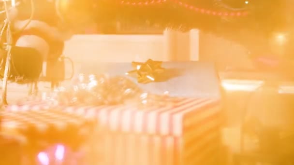 Closeup abstract footage of abstract golden glittering lights over Christmas tree and gift boxes — Stock Video
