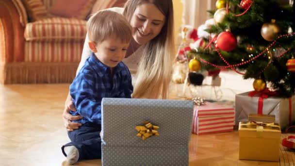 Feliz niño sonriente animando después de recibir regalo de Navidad por la mañana — Vídeos de Stock