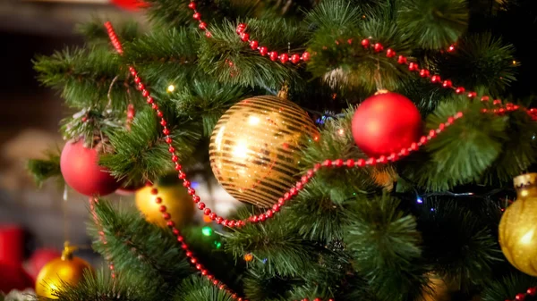 Imagem de close-up de bugigangas vermelhas e douradas, contas e guirlandas penduradas na árvore de Natal — Fotografia de Stock