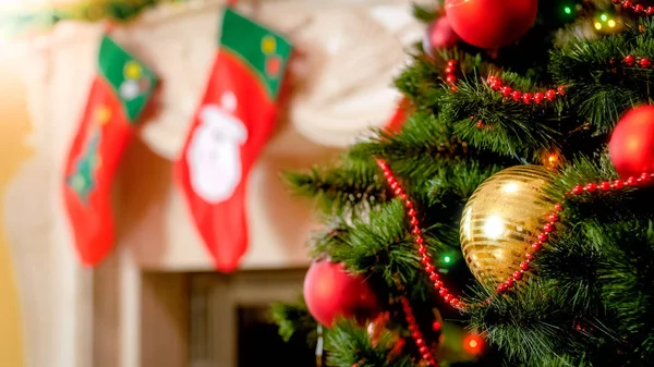 Closeup image of golden bauble and colorful lights on Christmas tree against mantelpiece — Stock Photo, Image