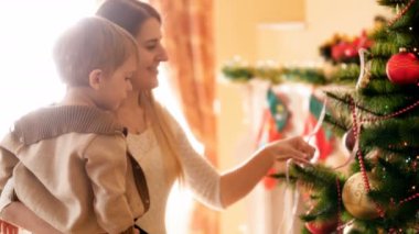 Mutlu genç anne ile küçük oğlu oturma odasında Noel ağacı süsleme