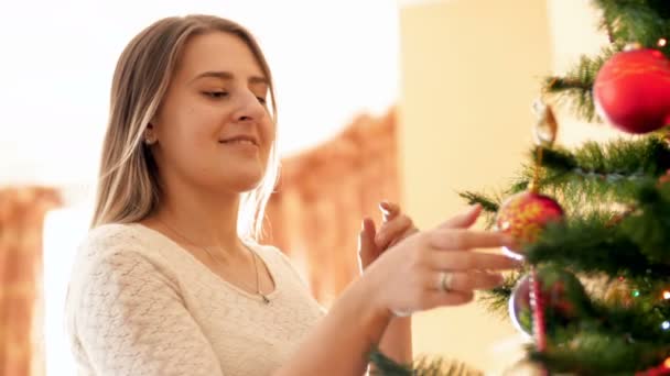 Όμορφη χαμογελαστή γυναίκα μαντηλιά χριστουγεννιάτικο δέντρο με στολίδια και ψάχνει τους — Αρχείο Βίντεο