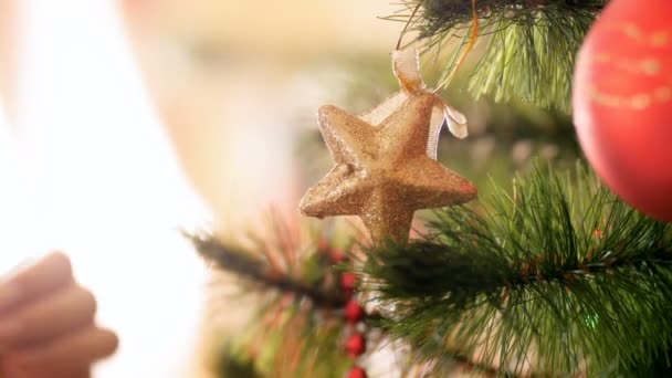Closeup 4k πλάνα του θηλυκού τα χέρια βάζοντας κόκκινο στολίδι στο χριστουγεννιάτικο δέντρο. Παρασκευάσματα για χειμερινές διακοπές και γιορτές — Αρχείο Βίντεο