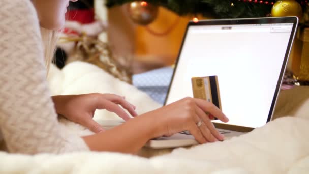 4k vídeo de jovem mulher fazendo compras online para o Natal. Ela está segurando cartão de crédito e usando laptop — Vídeo de Stock