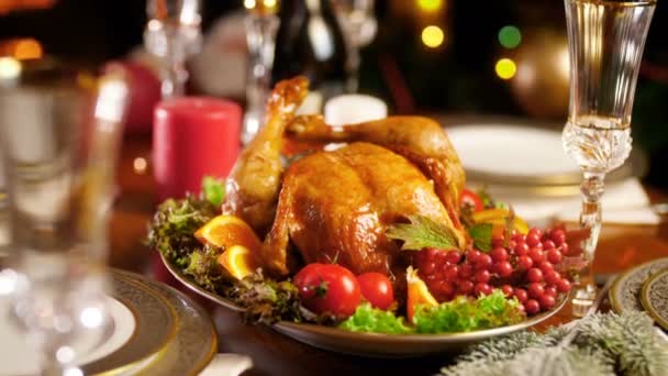 Closeup 4k footage of Christmas dinner table with baked chicken. Glowing colorful lights on backgorund — Stock Video