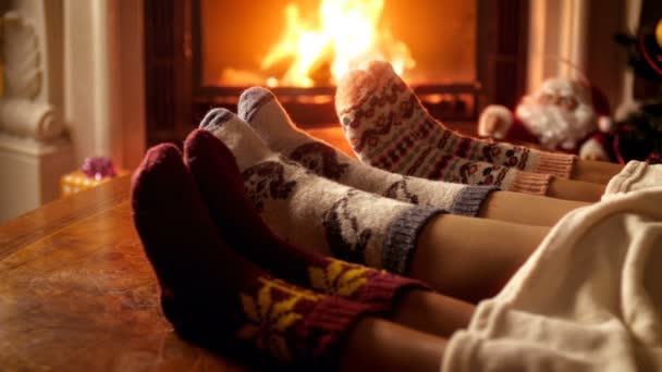 Nahaufnahme 4k-Video der Familie mit Wollsocken, die unter einer Decke liegen und sich am Kamin wärmen — Stockvideo