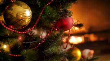 Closeup 4k video güzel dekore edilmiş yanan şömine karşı kırmızı ve altın baubles ile Noel ağacı. Kış kutlamalar ve tatil için mükemmel bir arka plan