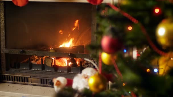 Closeup 4k imagens de queima de firepalce e árvore de Natal com luzes coloridas brilhantes — Vídeo de Stock