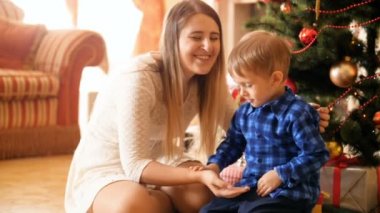 Gülen ağır çekim görüntüleri anne ile oynamak ve eğlenmek Noel ağacının altında sabah yürümeye başlayan çocuk