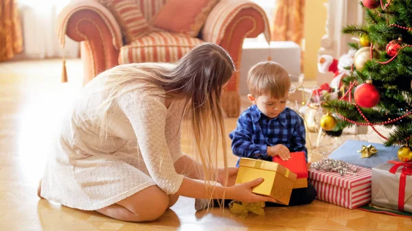 Joven madre dando caja de regalo de Navidad a su niño pequeño — Foto de Stock