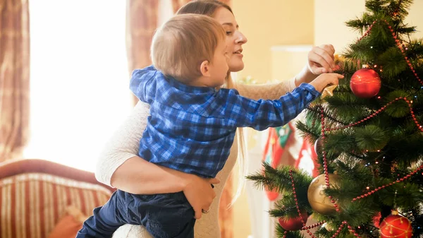 Retrato tonificado del niño pequeño adornando el árbol de Navidad con adornos —  Fotos de Stock